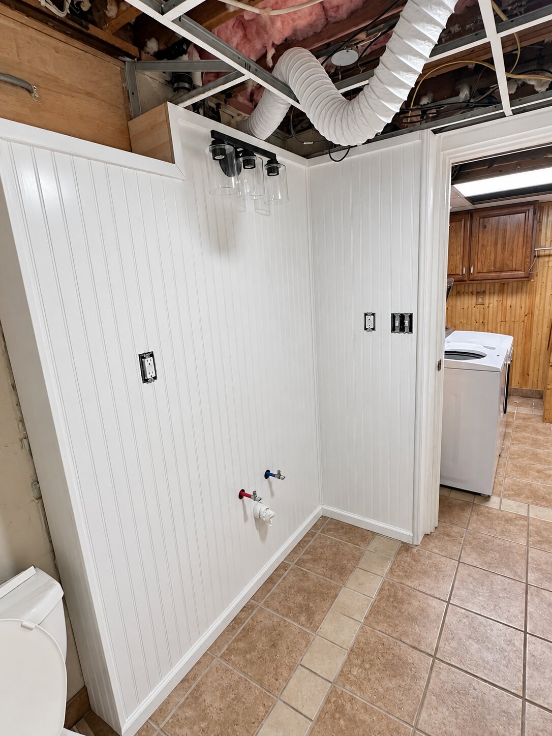 Bathroom conversion in progress with new wall paneling, trim and plumbing hookups